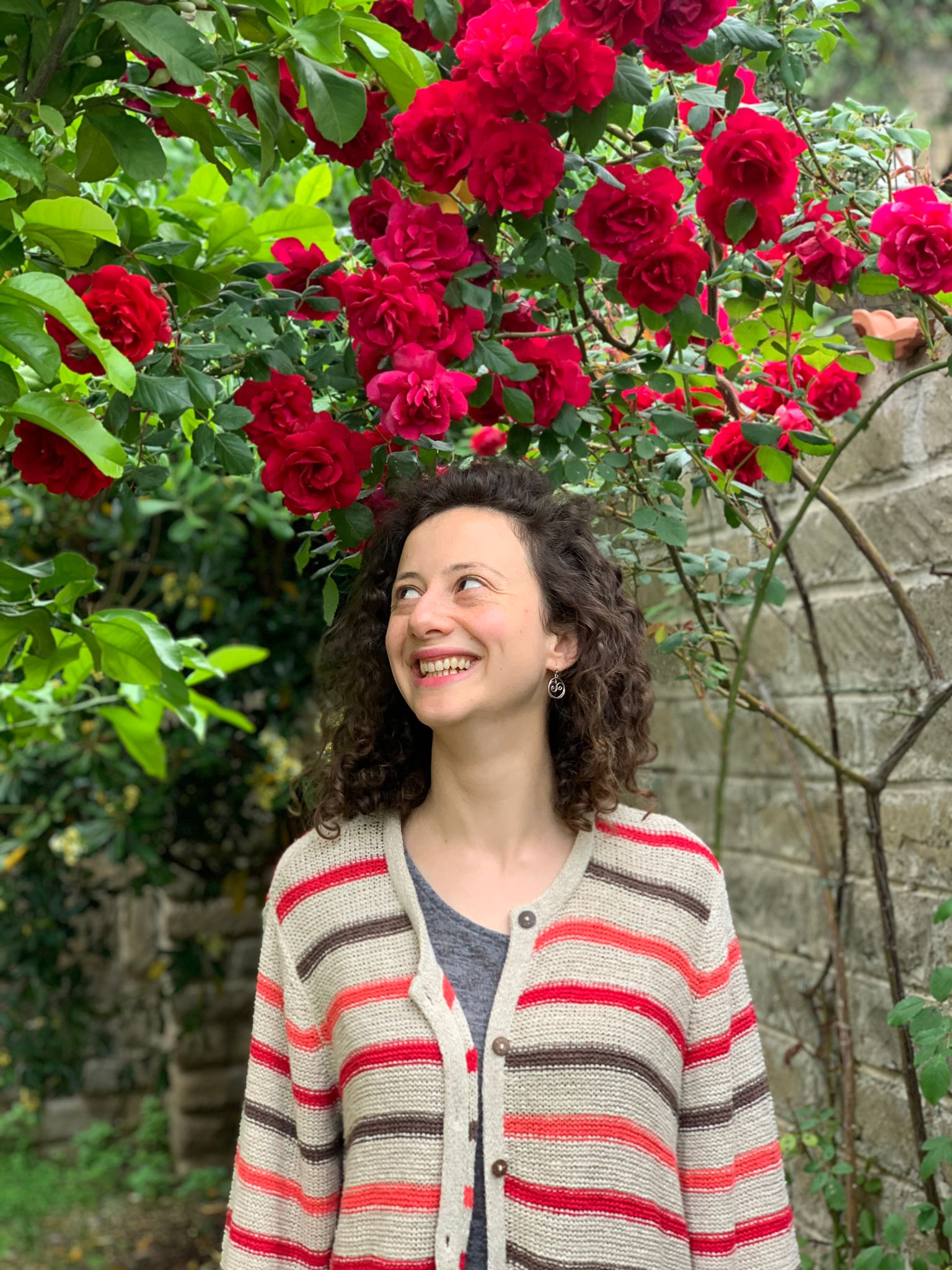 woman smiling under a bush of roses